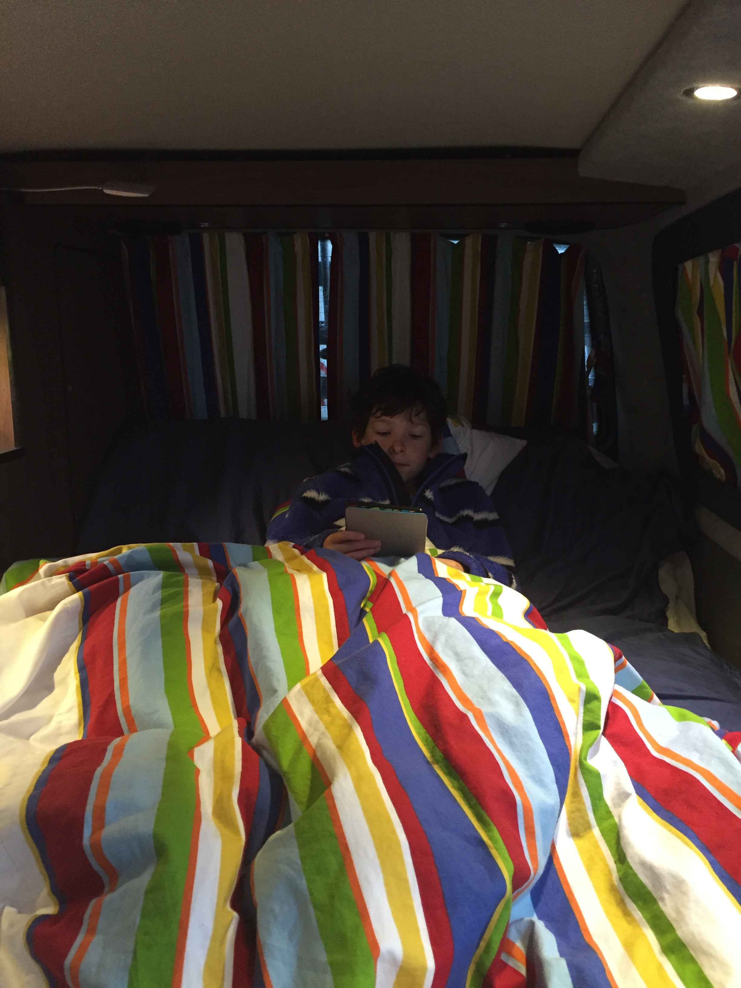 A VW T5 Campervan called Flo and Tom tucked up for an evening reading - Flo's stripy curtains are on every window for hire in Alfreton, Derbyshire